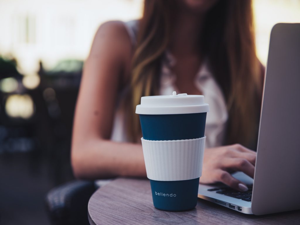 vrouw werkt naast koffiemok met logo