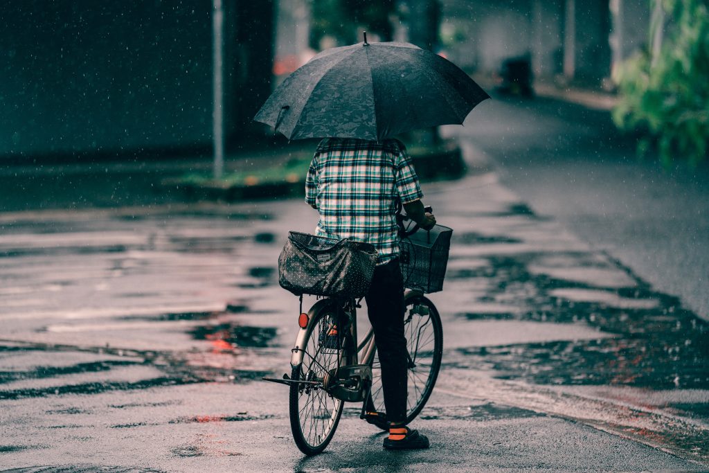 man op fiets met paraplu