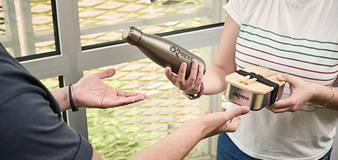 Iemand die een relatiegeschenk ontvangt van een bedrukte drinkfles en brooddoos