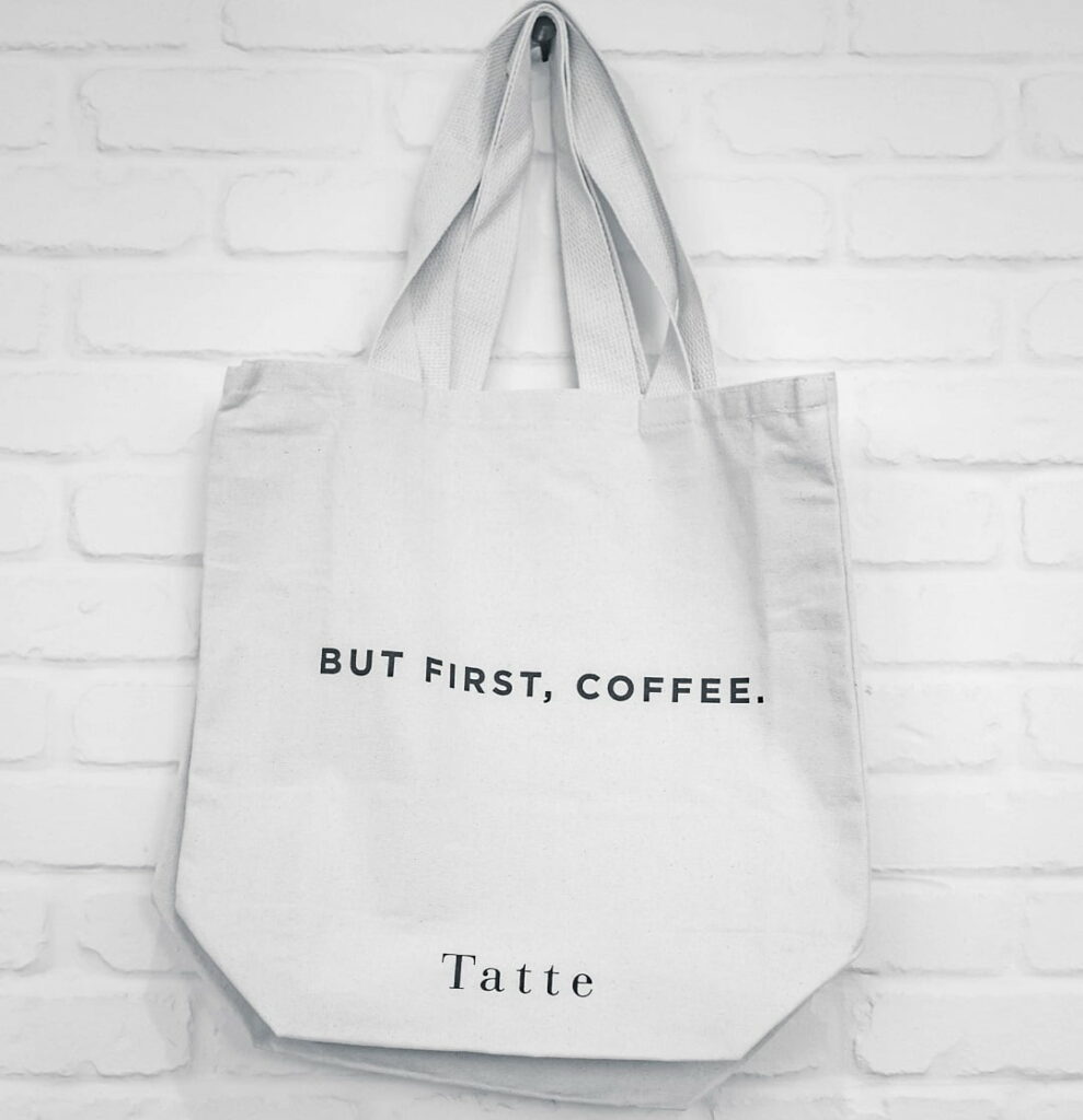 witte polyester tas met een logo bedrukt die aan de muur hangt