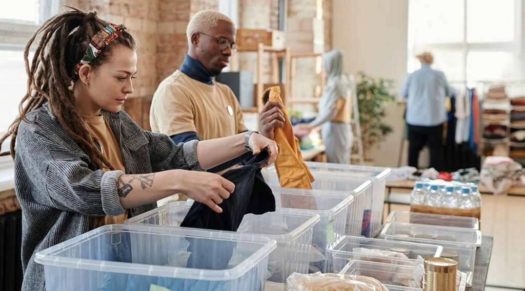 een man en vrouw die bezig zijn met het verzamelen van kleding voor een inzamelactie