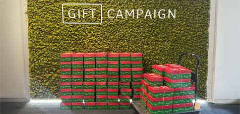Inzamelactie van Gift Campaign met alle geschenkdoosjes voor operatie kerstkind voor een groene muur