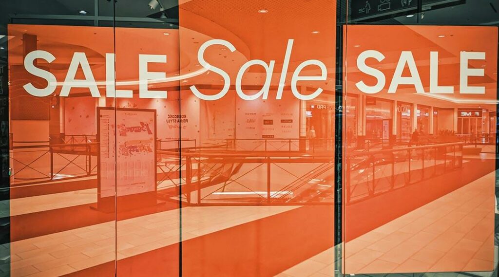 een etalage van een winkel met grote oranje sale borden