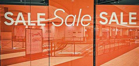 een etalage van een winkel met grote oranje sale borden voor massamarketing