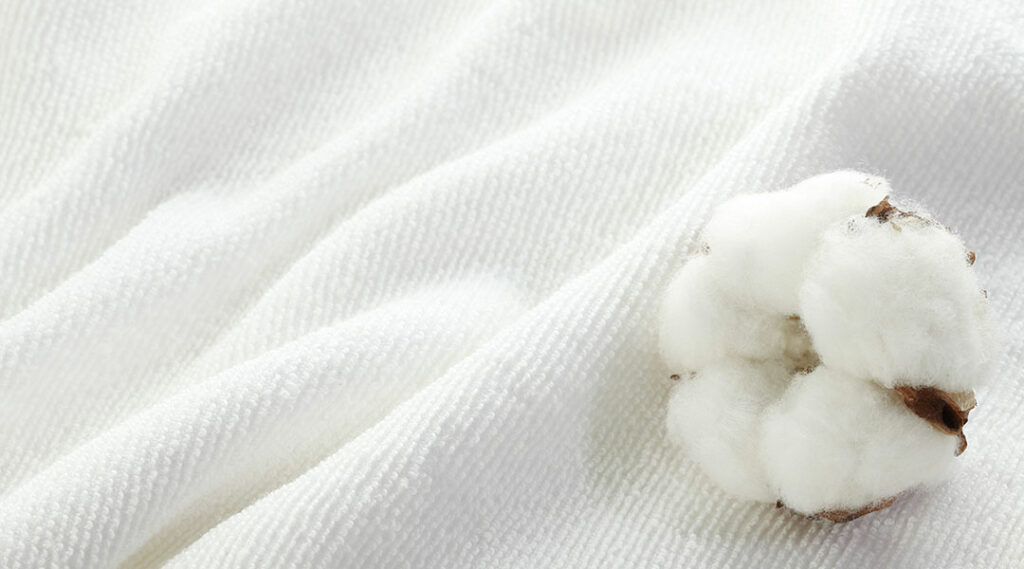 een katoenbloem die op een witte katoenen deken ligt