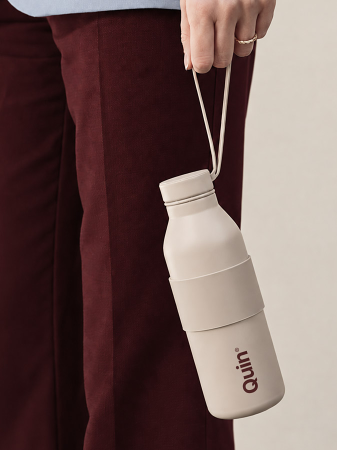 Crèmekleurige waterfles met een gedrukt logo en draagriem