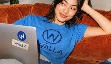 Vrouw werkt thuis op laptop met bedrukt blauw T-shirt met logo