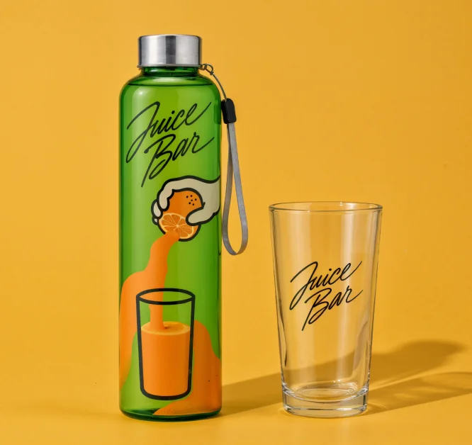 Een groene fles en een helder glas, beide voorzien van het logo van een op maat gemaakte sapbar